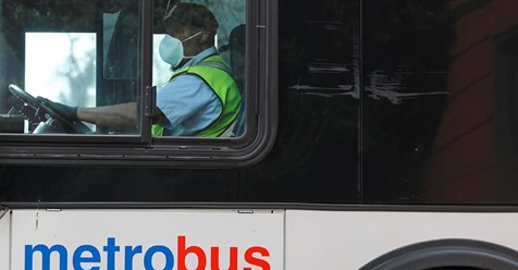 FILE PHOTO: A Washington Metro bus driver passes along a route wearing a face mask,