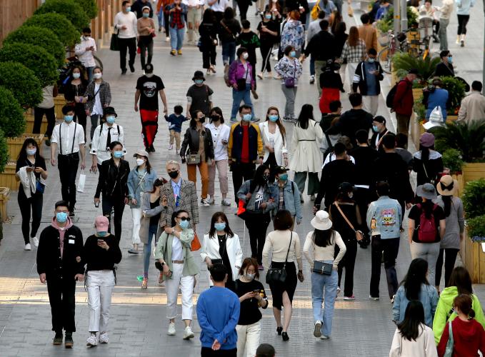 Pedestrians no longer practice safe "social distancing" but continue to wear protective face masks while visiting a popular entertainment area in Beijing on April 26.