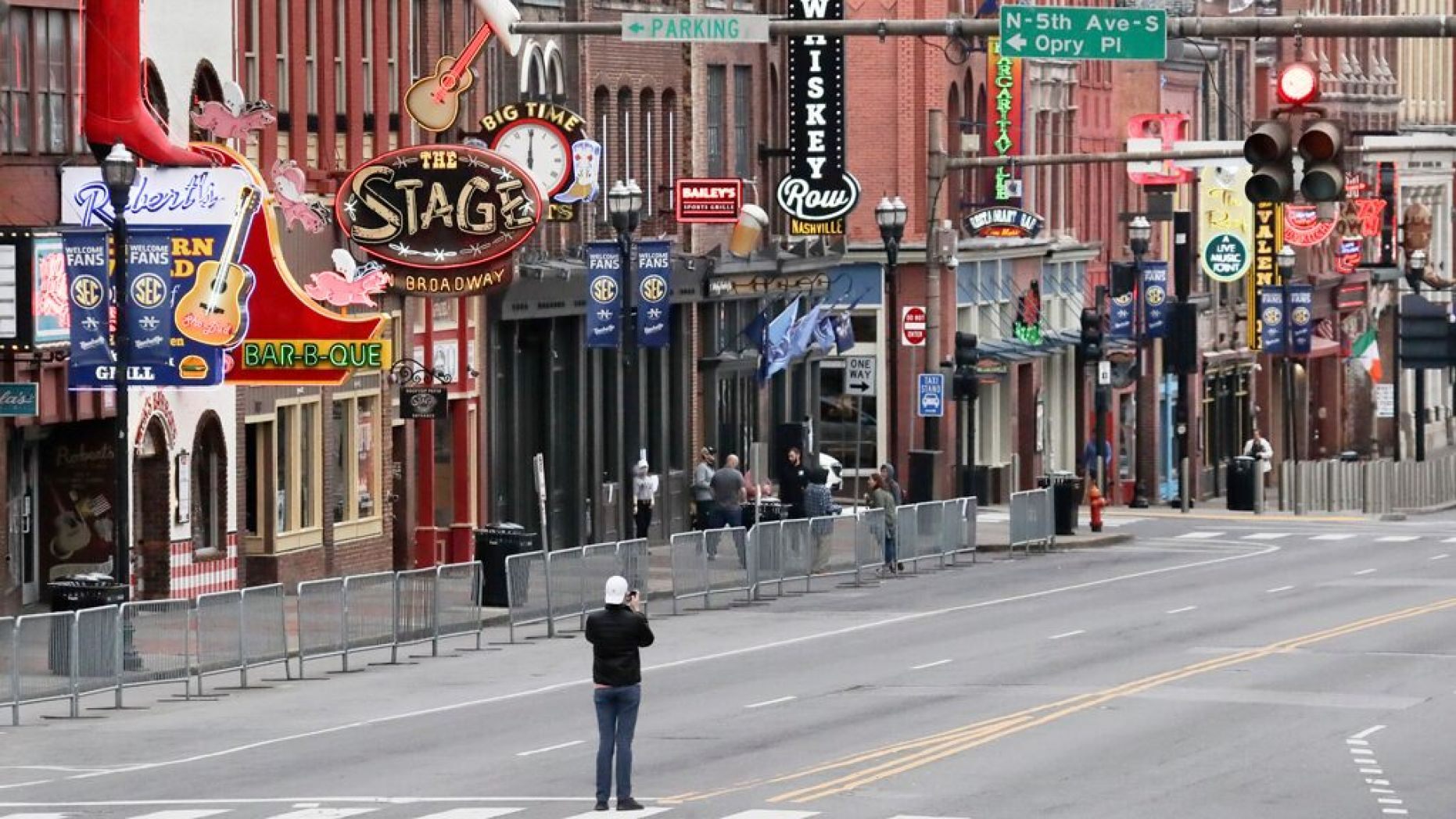 A man stands in the middle of Broadway to take a photo where the streets and sidewalks are normally filled in Nashville, Tenn. on March 23.