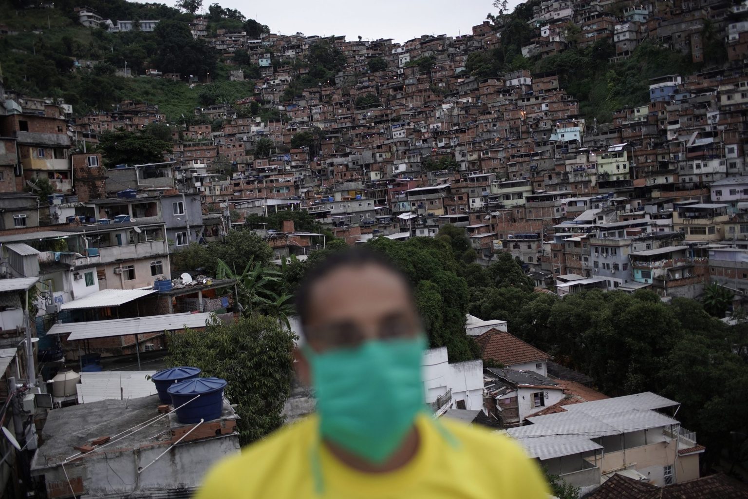 A worker protects himself against the coronavirus as he donates food to poor families in Turano favela,