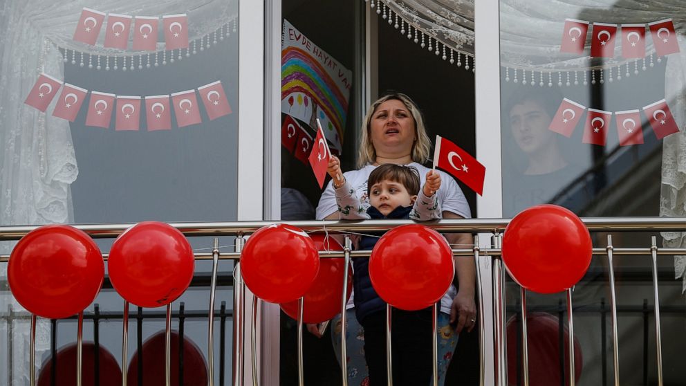 Local residents, in their flat due to the coronavirus, watch celebrations ahead of the National Sovereignty and Children's Day, in Istanbul, Wednesday, April 22, 2020.