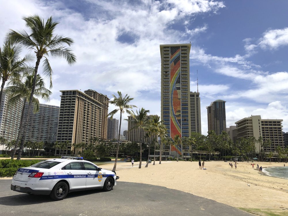 FILE - In this March 28, 2020, file photo, a police officer arrives to tell people to leave Waikiki Beach in Honolulu.