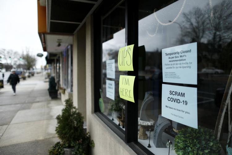 A person walks past a closed craft store March 17, 2020, in Havertown, Pa. Concerns about the new coronavirus have led to the temporary closure of many businesses and schools across the region.