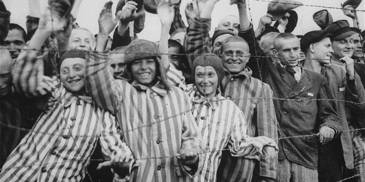 Survivors at the Dachau concentration camp cheer their liberation by US soldiers. 