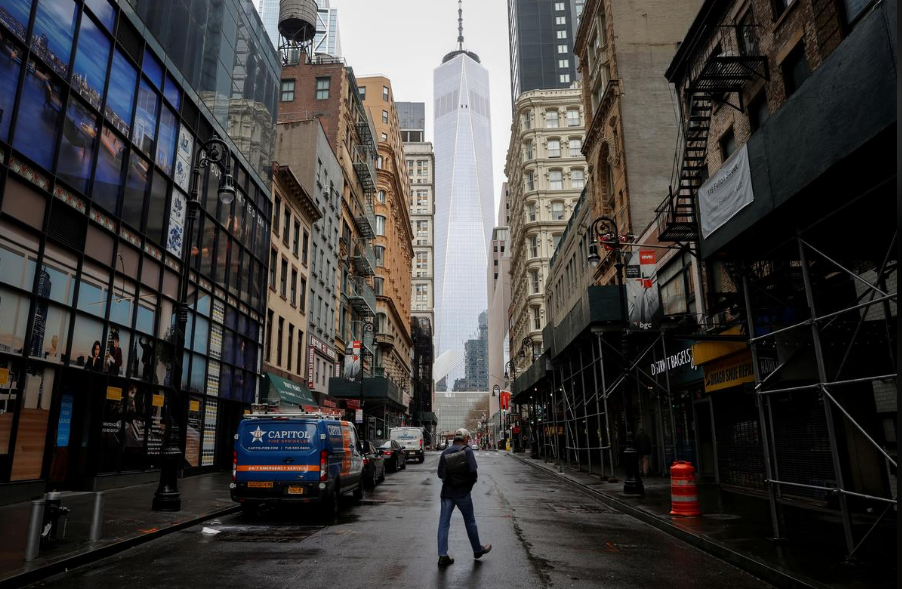 A man crosses a nearly deserted Fulton Street in the financial district in lower Manhattan during the outbreak of the coronavirus disease