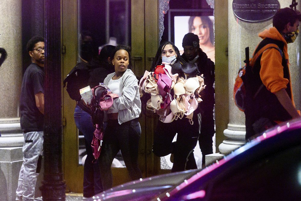 FILE - In this May 30, 2020, file photo, women carry merchandise from a Union Square Victoria's Secret store in San Francisco. Police say many of the smash-and-grab thefts have been carried out by caravans of well-coordinated criminals, 