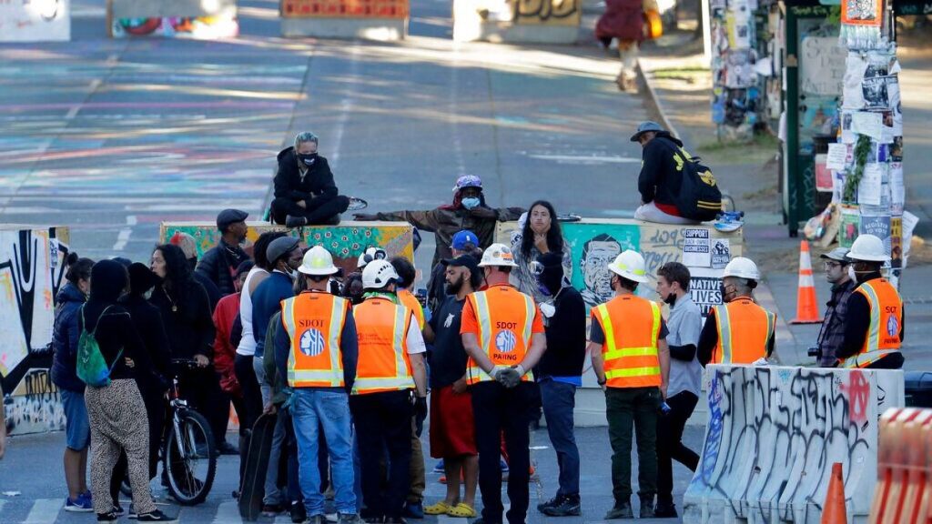 Seattle Department of Transportation workers talk with protest organizers near the Seattle Police Department East Precinct building after SDOT arrived at the CHOP ,