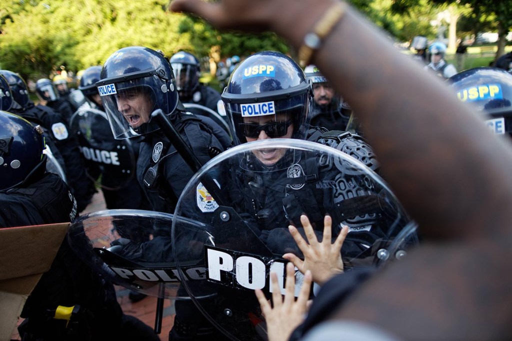 Police officers push back on people gathered outside the White House to protest George Floyd's death in May. 
