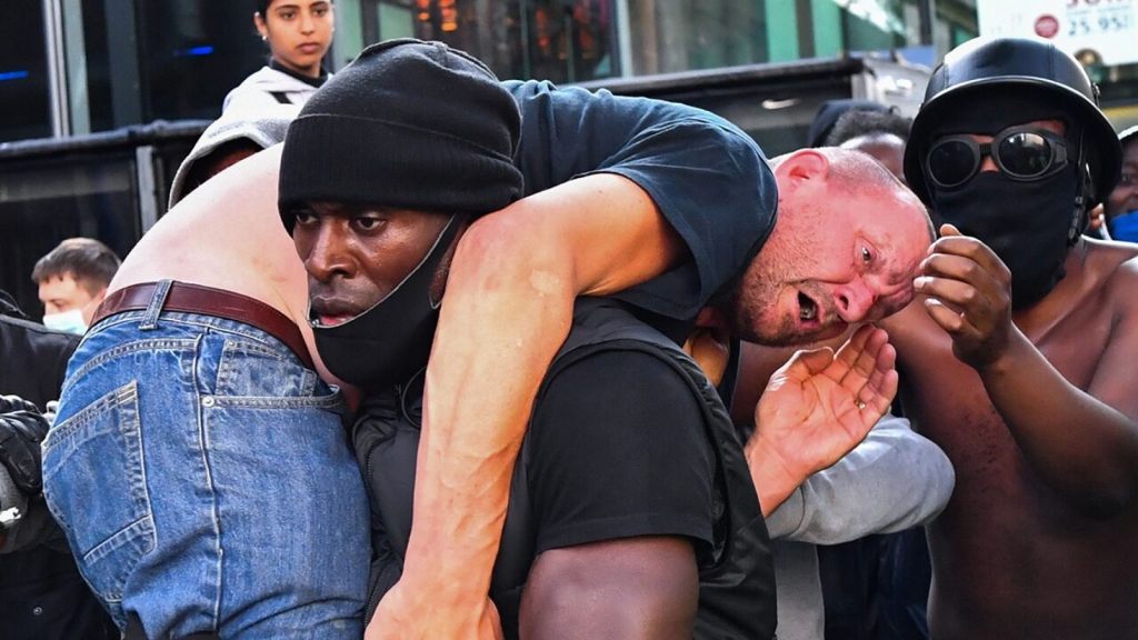 A protester carries an injured counterprotester to safety, near the Waterloo station during a Black Lives Matter protest in London, Britain, June 13, 2020.