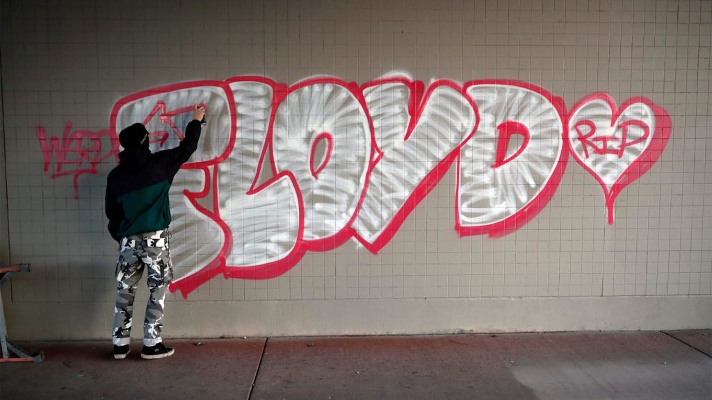 A protester spray paints George Floyd's name Friday, May 29, 2020, 