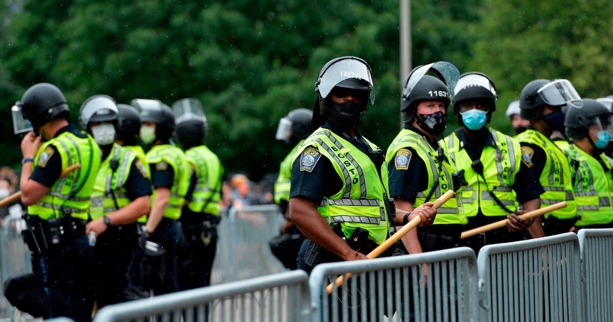 Police officers in riot gear stand guard outside the State House in Boston on June 27, 2020