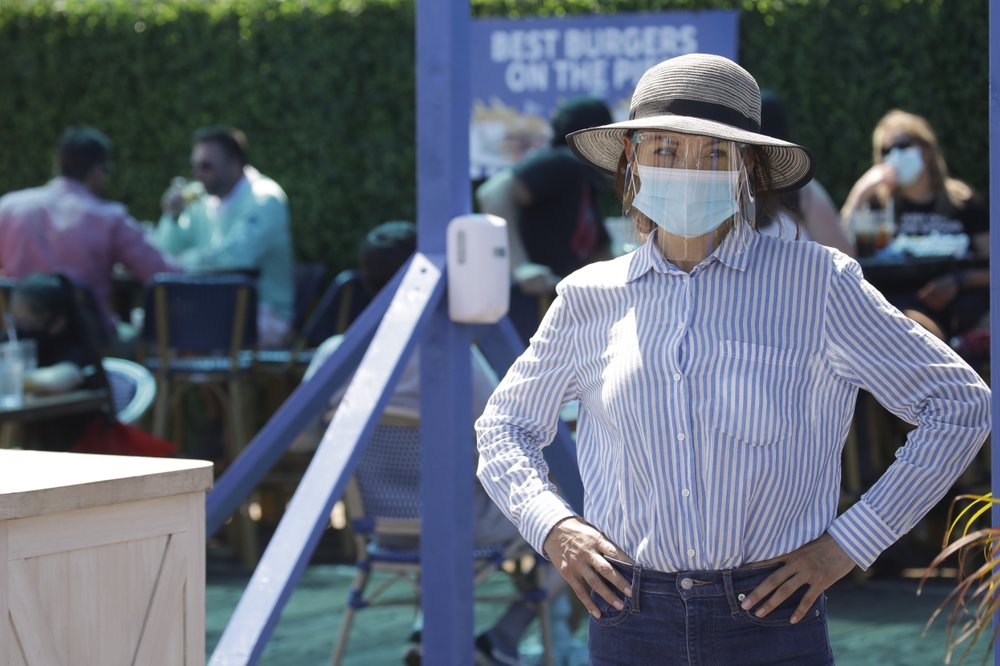 A hostess waits to sit customers on a restaurant at the pier Sunday, July 12, 2020, in Santa Monica, Calif.