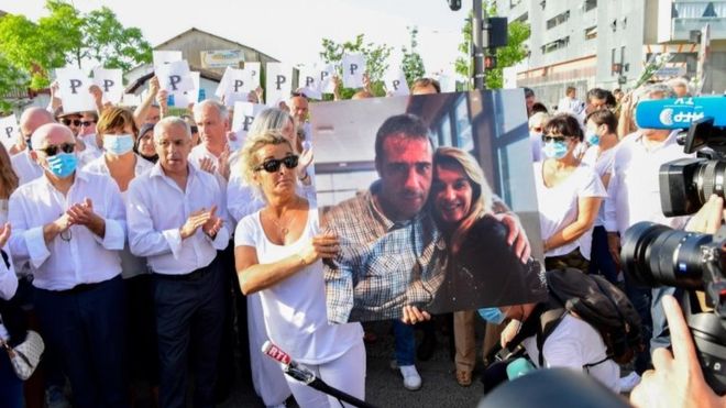 The wife of Philippe Monguillot, Veronique Monguillot (centre), holds a portrait of her husband during a protest march.