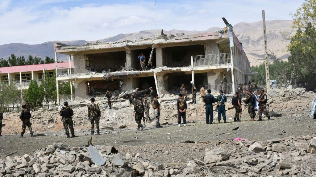 Afghan security personnel inspect the site of a car bomb blast,