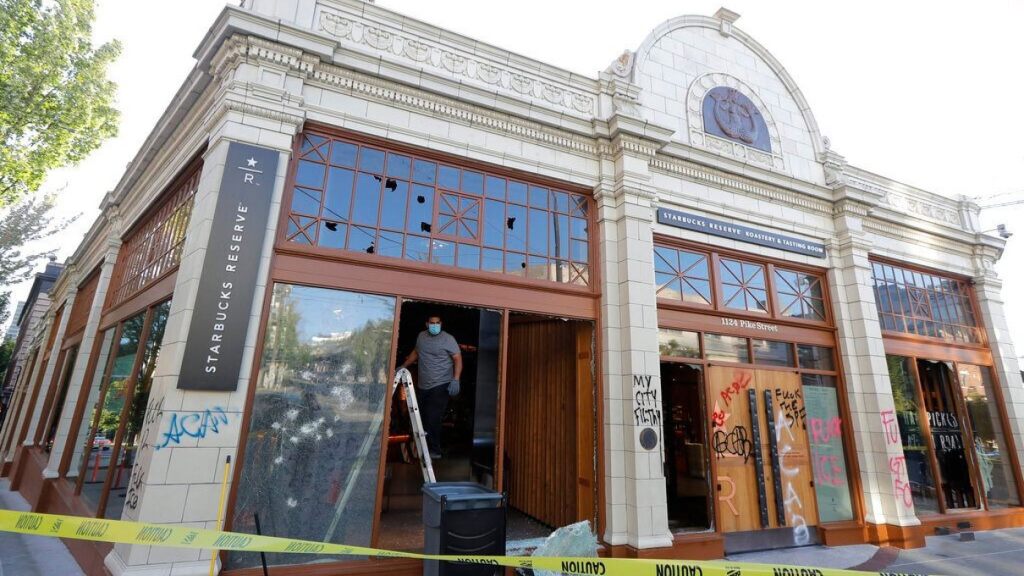 A worker clears glass from broken windows at the Starbucks Roastery, Sunday, July 19, 2020 in Seattle's Capitol Hill neighborhood. Protesters broke windows at the store earlier in the afternoon.