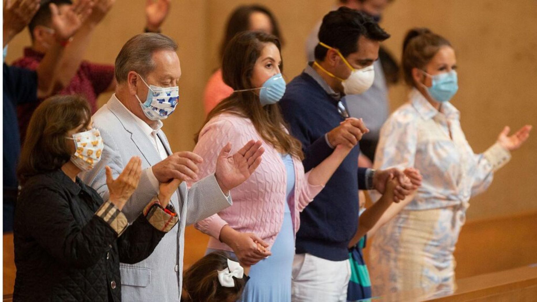 Family members hold hands as they pray at the first English Mass with faithful present at the Cathedral of Our Lady of the Angels in downtown Los Angeles,