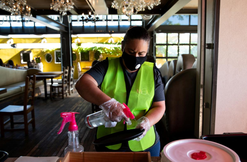 FILE PHOTO: An employee routinely sanitizes server trays at a reopened restaurant ,