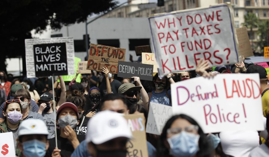 Demonstrators holds signs during a protest to demand the defunding of the Los Angeles school district police outside of the school board headquarters Tuesday,