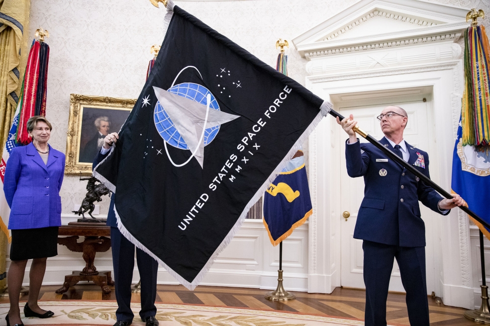 Gen. Jay Raymond (R), Chief of Space Operations, and CMSgt Roger Towberman (L), with Secretary of the Air Force Barbara Barrett present President Donald Trump with the official flag of the United States Space Force in the Oval Office at the White House in Washington, D.C.,