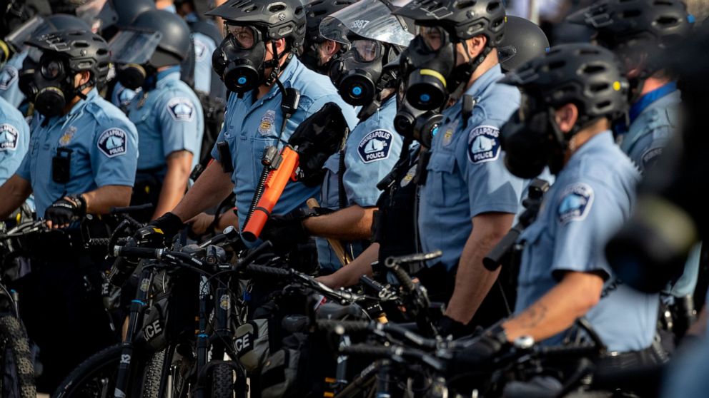 FILE - In this May 27, 2020, file photo, police gather en masse as protests continue at the Minneapolis 3rd Police Precinct in Minneapolis.