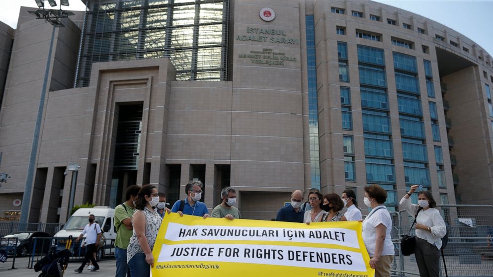 Protesters from Amnesty International stage a protest outside a court in Istanbul, Friday, July 3, 2020, where the trial of 11 prominent human rights activists for terror-related charges and adjourned proceedings was continuing.