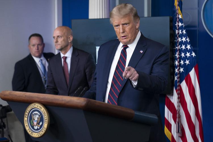 President Donald Trump speaks, accompanied by Food and Drug Administration Commissioner Dr. Stephen Hahn, center, during a media briefing in the James Brady Briefing Room of the White House, Sunday, Aug. 23, 2020,