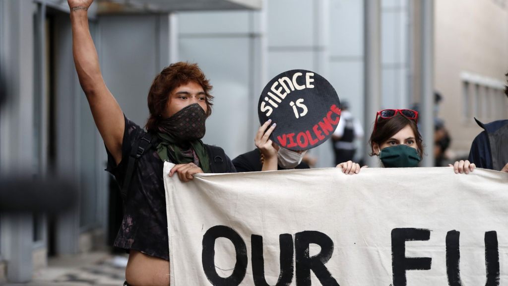 Protesters hold a banner as Ariel Atkins (not seen), a lead organizer for Black Lives Matter Chicago, talks to reporters Monday, Aug. 10, 2020, outside the Chicago Police Department's District 1 station in Chicago.