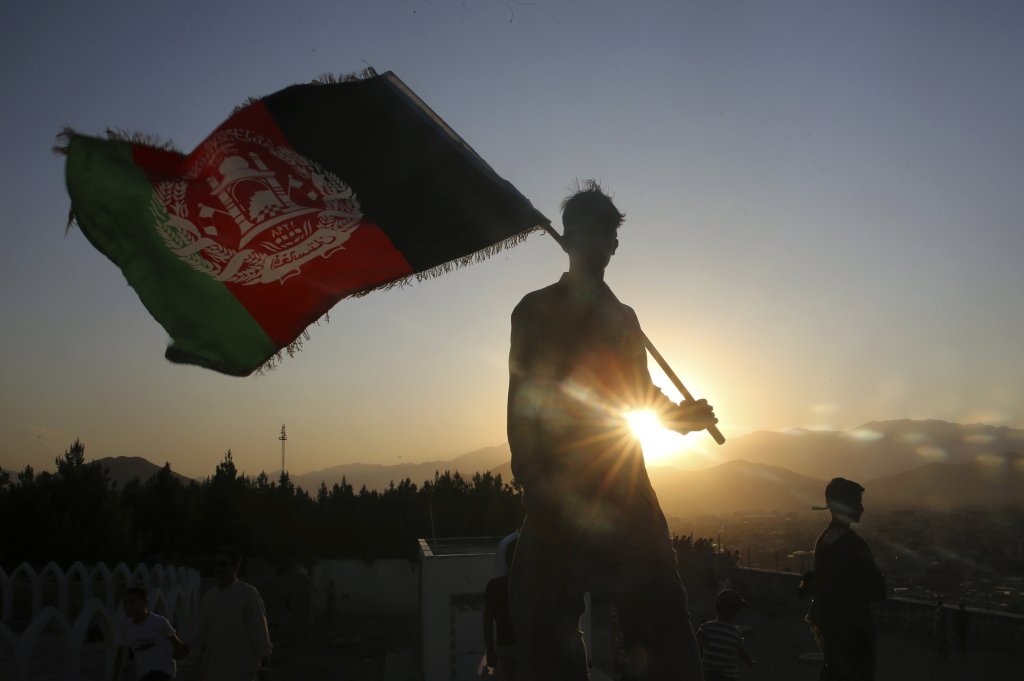 FILE - In this Aug. 19, 2019, file photo, a man waves an Afghan flag during Independence Day celebrations in Kabul, Afghanistan.