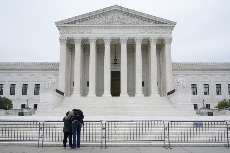 A woman and man pray outside the Supreme Court on Capitol Hill in Washington, Tuesday, Oct. 27, 2020, the day after the Senate confirmed Amy Coney Barrett to become a Supreme Court Justice.