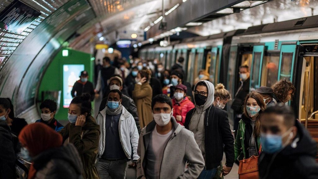 Commuters wearing face masks walk on the platform, of a Paris subway, Sunday Oct.25, 2020.