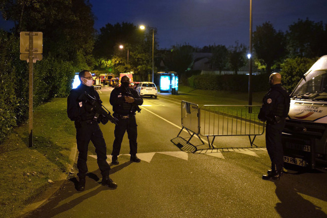 French police officers stand guard on a street in Eragny where an attacker was shot dead by policemen after he decapitated a man today.