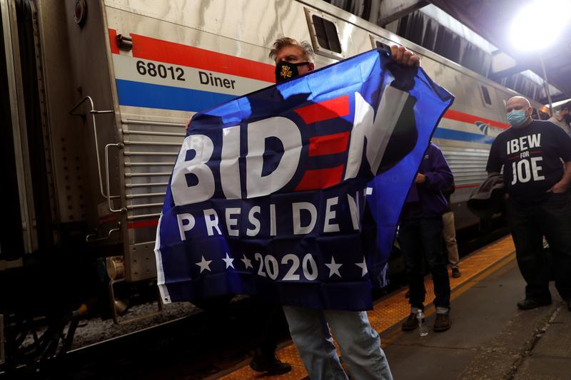 FILE PHOTO: A supporter of U.S. Democratic presidential candidate and former Vice President Joe Biden holds a flag as he stands next to Biden's campaign train during a campaign stop in Pittsburgh, Pennsylvania, U.S., September 30, 2020.