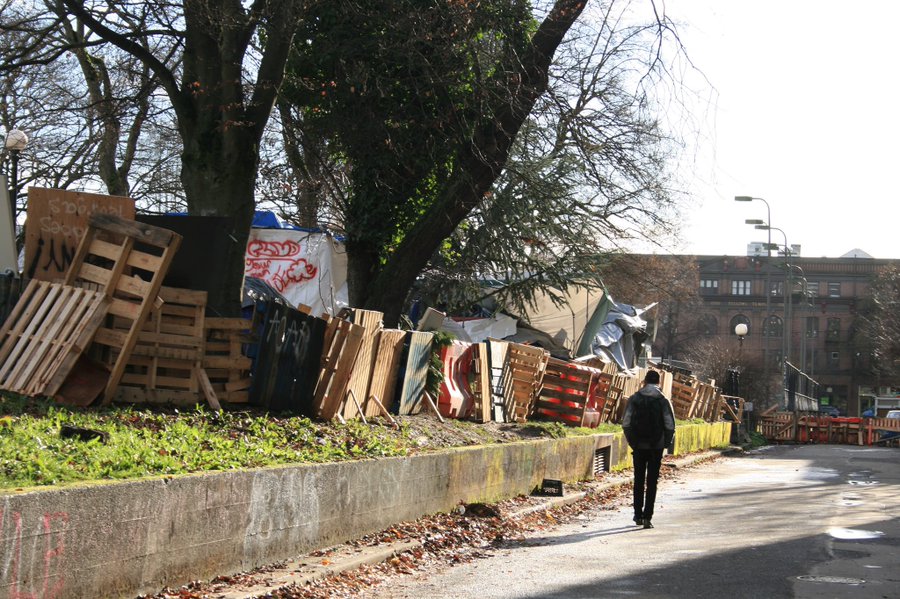 Man walks by barricades surrounding homeless encampment on Nagle Pl. Seattle,
