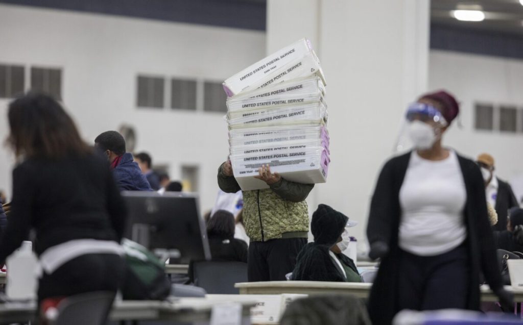A worker with the Detroit Department of Elections carries empty boxes used to organize absentee ballots after nearing the end of the absentee ballot count,