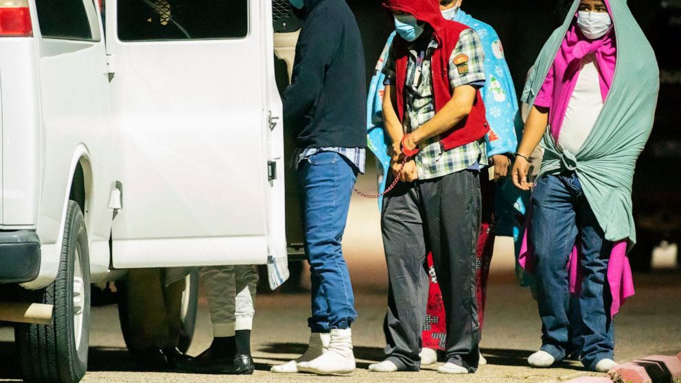 People are handcuffed together in pairs and loaded into vans as police investigate a possible human smuggling operation, Thursday night, Dec. 4, 2020, in Houston.