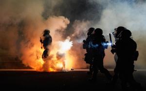 Police walk through a fiery street on 100th day of Portland violence.
ALLISON DINNER/AFP via Getty Images