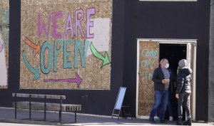 FILE - In this Jan. 19, 2021, file photo, diners exit a restaurant with open notices scrawled on plywood sheets covering the establishment's windows, a block south of the State Capitol in downtown Denver. Not willing to wait for more federal help, states have been moving ahead with their own coronavirus relief packages.