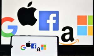 The logos of Google, Apple, Facebook, Amazon, and Microsoft are displayed on a mobile phone and a laptop screen in London on Dec. 18, 2020.