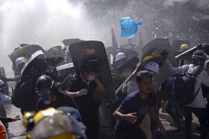 Protesters are dispersed as riot police fire tear gas during a demonstration in Yangon, Myanmar, Monday, March 8, 2021.