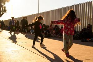Children play as families of asylum seekers wait outside the El Chaparral border crossing port as they wait to cross into the United States in Tijuana, Baja California state, Mexico on February 19, 2021.