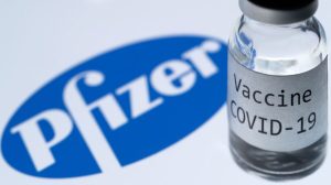 A bottle reading "COVID-19 Vaccine" is seen next to the Pfizer company logo in Paris, France, on Nov. 23, 2020. (Joel Saget/AFP via Getty Images)