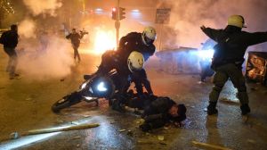 A policeman lays injured on the road after an attack by protesters as his colleagues try to help him during clashes in Athens, Tuesday, March 9, 2021.
