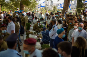 Civilians and soldiers gather by graves of Israeli soldiers during a Memorial Day ceremony for fallen soldiers and victims of attacks, at the military cemetery at Mount Herzl, in Jerusalem, Wednesday, April 14, 2021.