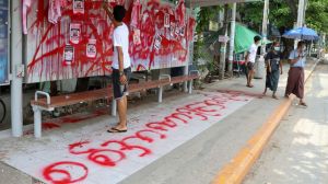An anti-coup protester uses red paint as he writes slogans at a bus stop on Wednesday April 14, 2021 in Yangon, Myanmar.