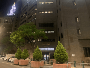 The Metropolitan Correctional Center in Lower Manhattan on May 1, 2021, with New York City Hall illuminated in the background.