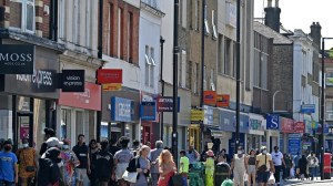 Pedestrians, some wearing face coverings due to Covid-19, walk past shops in Hounslow,