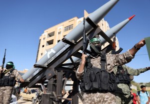 Members of the Ezz-Al Din Al-Qassam Brigades, the armed wing of the Hamas movement, parade on trucks with rockets in a street in Khan Yunis, in the southern Gaza Strip,