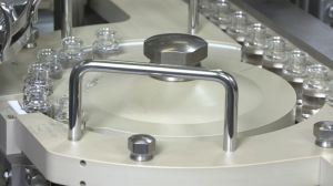 In this undated image from video provided by Biogen in May 2021, vials of the medication aducanumab are handled by machines during manufacturing in Switzerland.