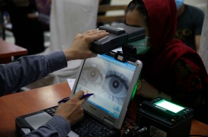 An employee scans the eyes of a woman for biometric data needed to apply for a passport, at the passport office in Kabul, Afghanistan, on June 30, 2021. | Rahmat Gul/AP Photo