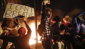 In this May 28, 2020, protesters demonstrate outside of a burning Minneapolis 3rd Police Precinct in Minneapolis. (AP Photo/John Minchillo, File) 